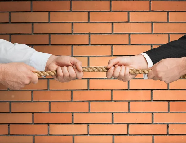 Business people pulling rope in opposite directions at office