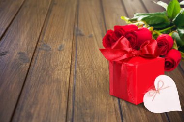 kırmızı güller ve hediye ahşap arka planda