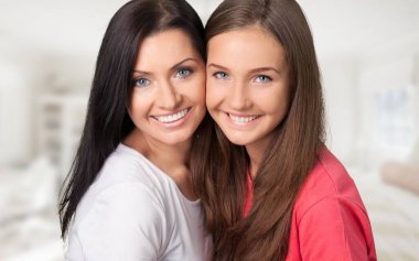 Anne ve kızı kucaklıyor ve gülümsüyor.  