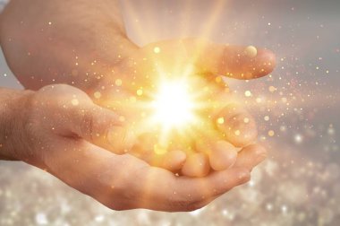 Parlayan bir ışığı tutan eller