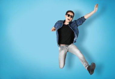 Genç yakışıklı adam mavi arka planda zıplıyor