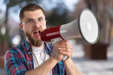 Genç adam elinde megafon tutuyor ve tanıtımını yapıyor  