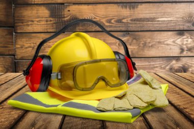 Güvenlik kaskı ve tahta arka planda koruyucu eldivenler.