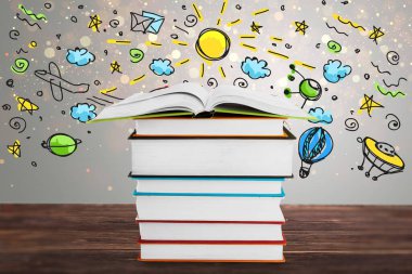 Ahşap masada renkli çizimleri olan bir yığın kitap.