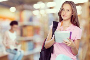Kütüphanede notlar alan genç bir kadın.
