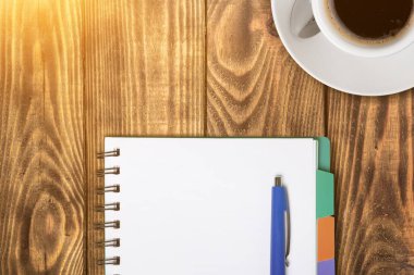 Üzerinde kahve fincanı ve tahta kalem olan açık defter manzarası