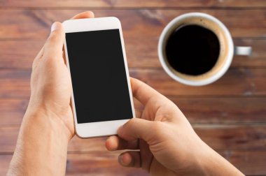 Kahve ve cep telefonu olan erkek elleri 