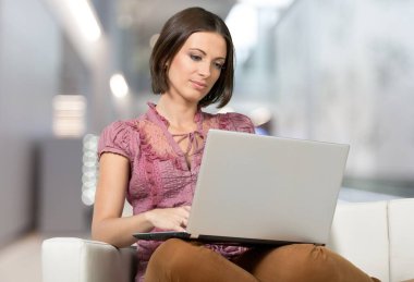 oturma odasında kanepede dizüstü kullanan kadın  