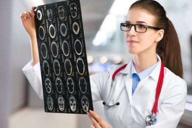 Steteskop ve röntgen görüntüsü olan genç bir kadın doktor.