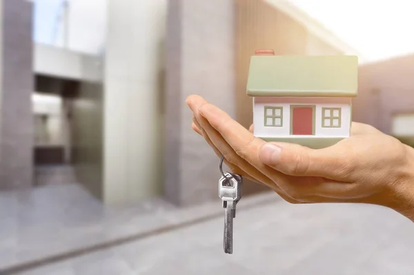 Hand Hält Hausmodell Und Schlüssel Auf Hintergrund — Stockfoto