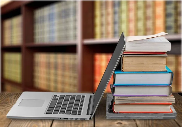 Stack of books and laptop, modern education background