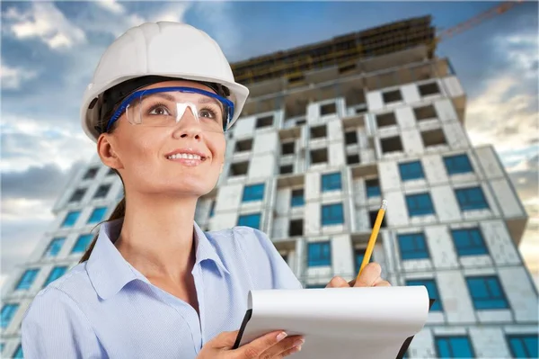 戴头盔的年轻工程师 在建筑工地的背景上有蓝图 — 图库照片