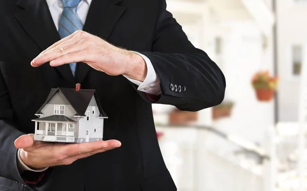 businessman holding house model in hands