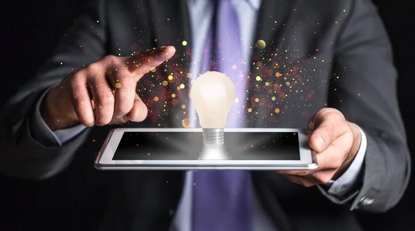 businessman holding tablet with glowing light bulb