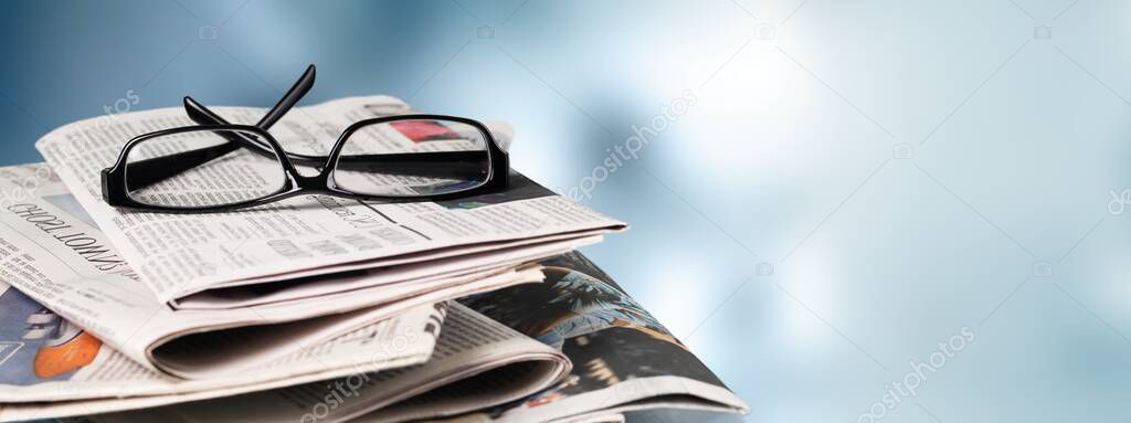 Stack of newspapers and eyeglasses on  background