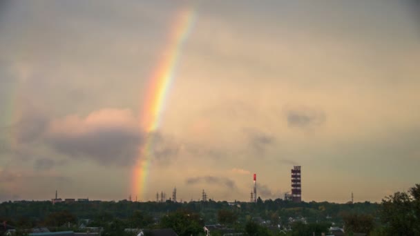 Felhők az égen, és a Rainbow haladnak át a várost, az épületek és a növény csövek. Idő telik el — Stock videók