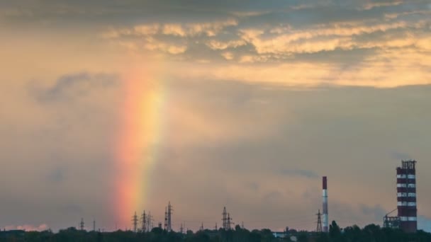 Felhők az égen, és a Rainbow haladnak át a várost, az épületek és a növény csövek. Idő telik el — Stock videók