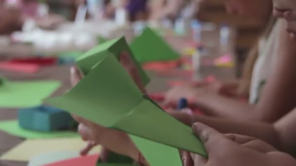 Τα παιδιά κάνουν χειροτεχνίες από χαρτί στο τραπέζι, χειροποίητα — Αρχείο Βίντεο