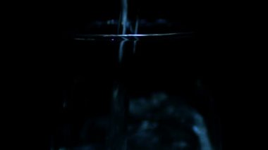 Su siyah arka plan üzerine saydam bir cam içine dökülür. Ağır çekim