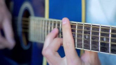 Adam akustik gitar çalıyor.