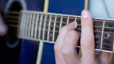 Adam akustik gitar çalıyor.