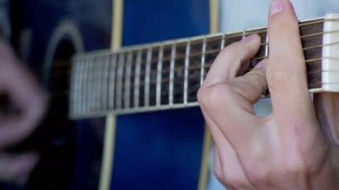 Adam akustik gitar çalıyor.