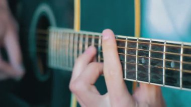 Adam akustik gitar çalıyor.