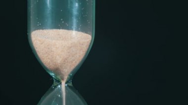 Siyah arka plan üzerinde kum saati, kum içine düşüyor