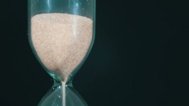 Siyah arka plan üzerinde kum saati, kum içine düşüyor