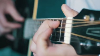 Adam akustik gitar çalıyor.
