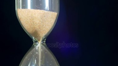 Siyah arka plan üzerinde kum saati, kum içine düşüyor