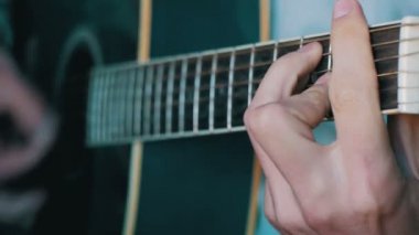 Adam akustik gitar çalıyor.