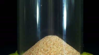 Siyah arka plan üzerinde kum saati, kum içine düşüyor