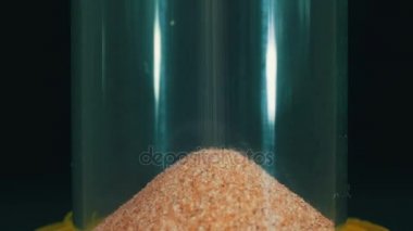 Siyah arka plan üzerinde kum saati, kum içine düşüyor