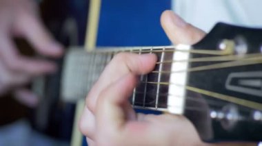 Adam akustik gitar çalıyor.