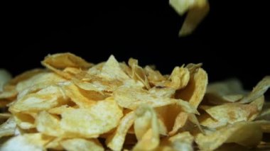 Adam ağır çekimde siyah arka plan üzerinde ahşap bir masa üzerinde elle patates cipsi alır