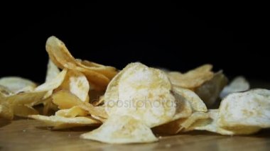 Patates cipsi yavaş siyah arka plan üzerinde ahşap bir masa üzerine düşüyor