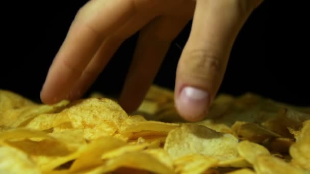 Man neemt de aardappel Chips met de hand op een houten tafel op zwarte achtergrond in Slow Motion — Stockvideo