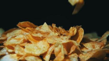 Adam ağır çekimde siyah arka plan üzerinde ahşap bir masa üzerinde elle patates cipsi alır