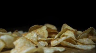 Patates cipsi yavaş siyah arka plan üzerinde ahşap bir masa üzerine düşüyor