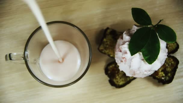 Joghurt wird in Zeitlupe in ein transparentes Glas auf einem Holztisch gegossen — Stockvideo