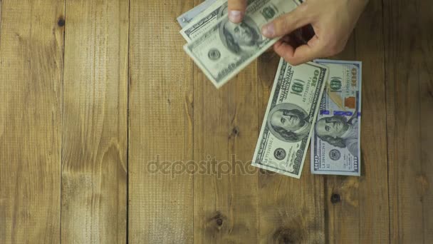 Las manos del hombre consideran billetes de dólar en una mesa de madera . — Vídeos de Stock