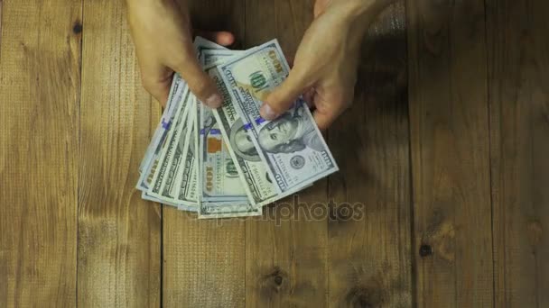 Ο άνθρωπος τα χέρια θεωρούν τραπεζογραμματίων δολαρίων σε ένα ξύλινο τραπέζι. — Αρχείο Βίντεο