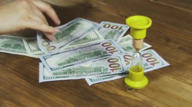 Bir ahşap masa ve kum saati düşen Doları banknot