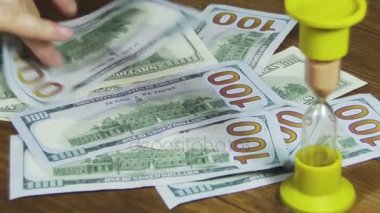 Bir ahşap masa ve kum saati düşen Doları banknot