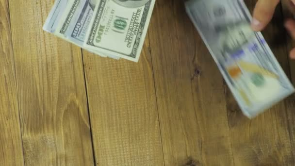 Банкноты в долларах падают на деревянный стол — стоковое видео
