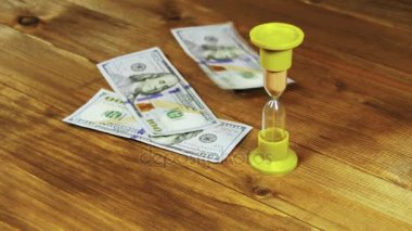 Bir ahşap masa ve kum saati düşen Doları banknot