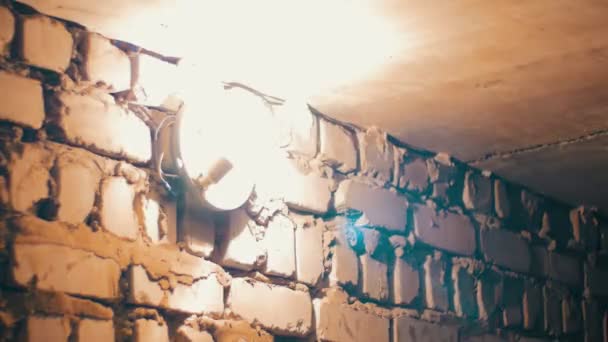 На каменной стене загорается лампа накаливания — стоковое видео