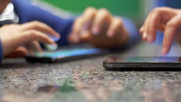 Niño jugando con el teléfono sentado a la mesa en un café con la gente . — Vídeos de Stock