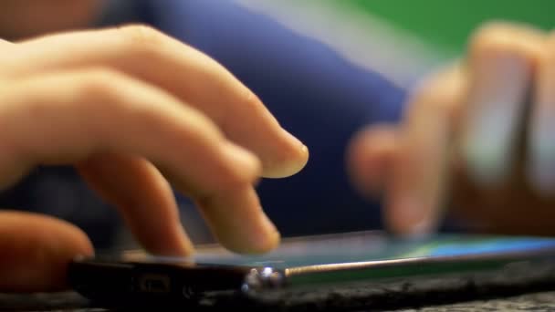 Niño jugando con el teléfono móvil en la mesa — Vídeo de stock